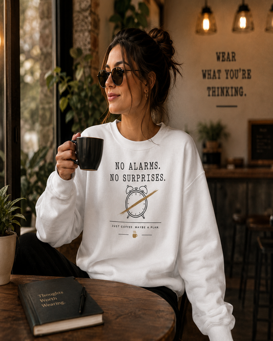 Woman wearing a white Morning Terms & Conditions sweatshirt and holding coffee in a café