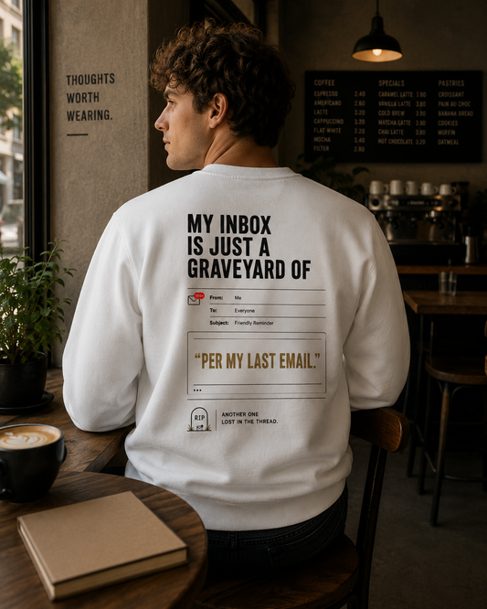 Man wearing a white Inbox Archaeologist sweatshirt with back print in a café