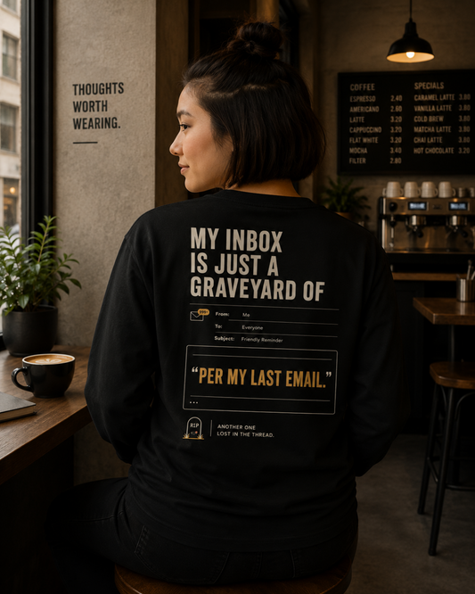 Woman wearing a black Inbox Graveyard long-sleeve shirt with back print in a café